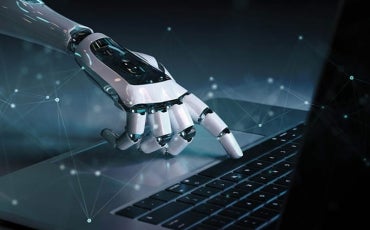 A robotic hand with glowing blue accents is pressing keys on a laptop keyboard, with digital network lines and dots overlaying the dark background, symbolizing artificial intelligence and technology.
