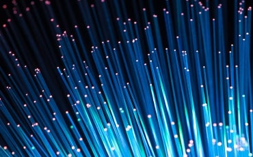 shutterstock_194741123_870x500.jpg Close-up of glowing blue fiber optic cables with pink-tipped ends, radiating outward against a dark background, representing high-speed data transmission and modern technology.