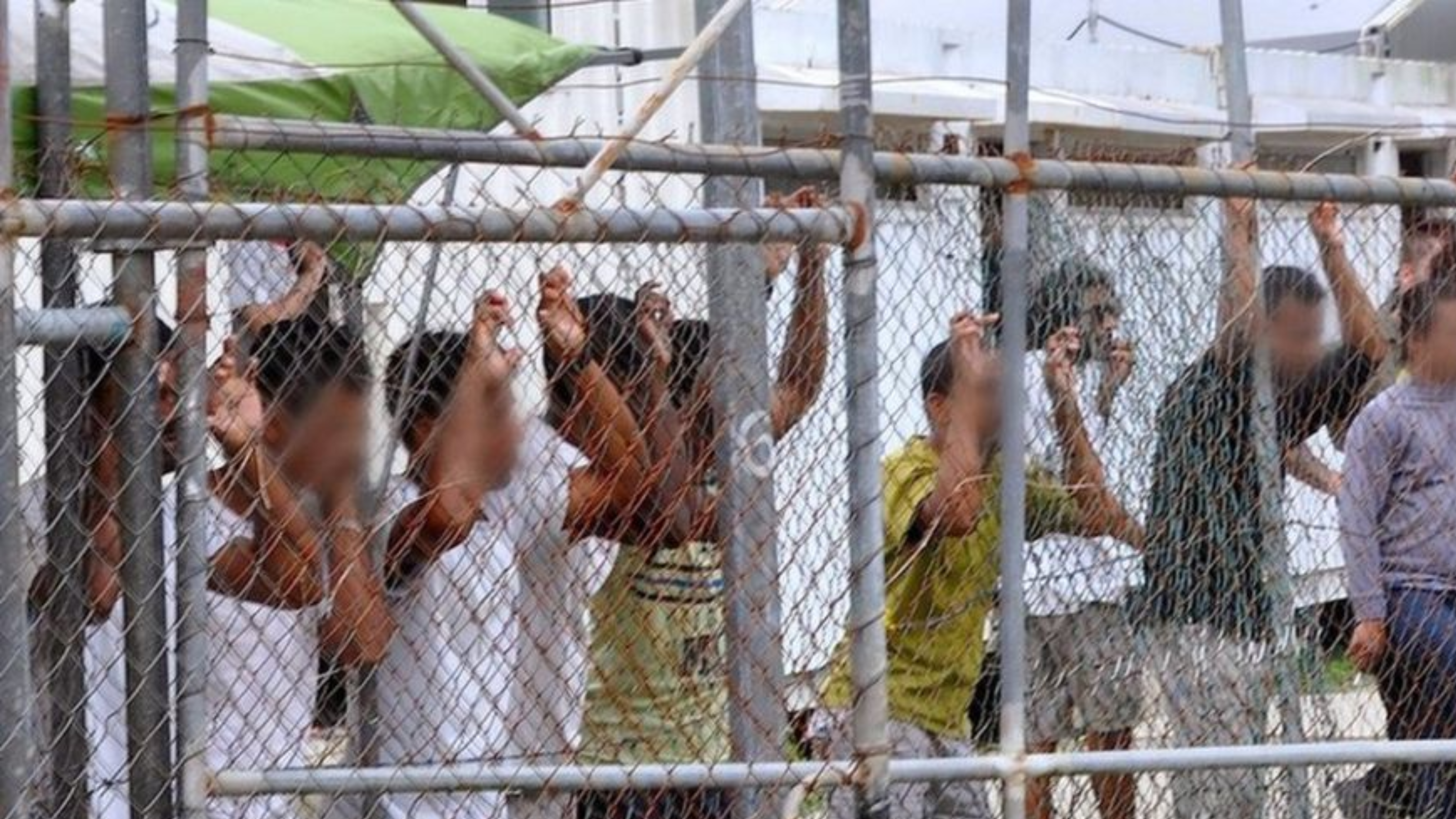 40 Years Refugee 2 people behind mesh fencing in an immigration centre