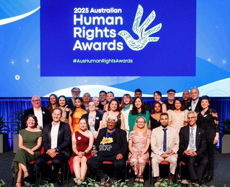 a large group of diverse people on a stage with blue background