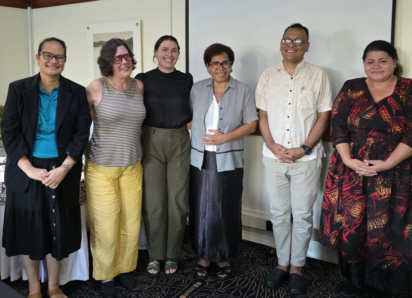 Six representatives from the Commission and FHRADC standing together at a workshop, smiling and facing the camera.