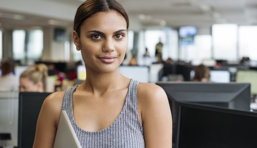 Portrait of ethnic aboriginal Australian businesswoman in a office holding a laptop computer.