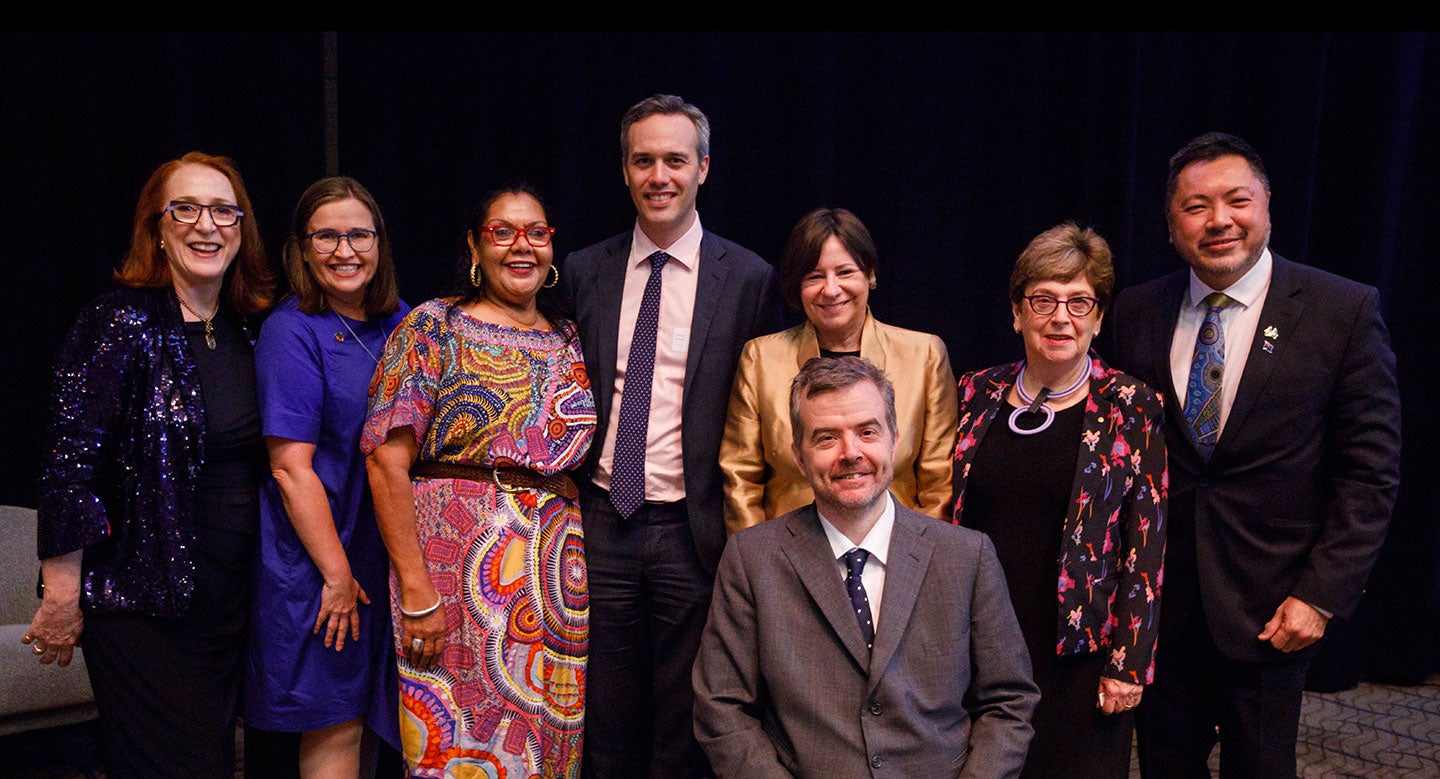 A group photo of all eight Commissioners smiling at the camera. T