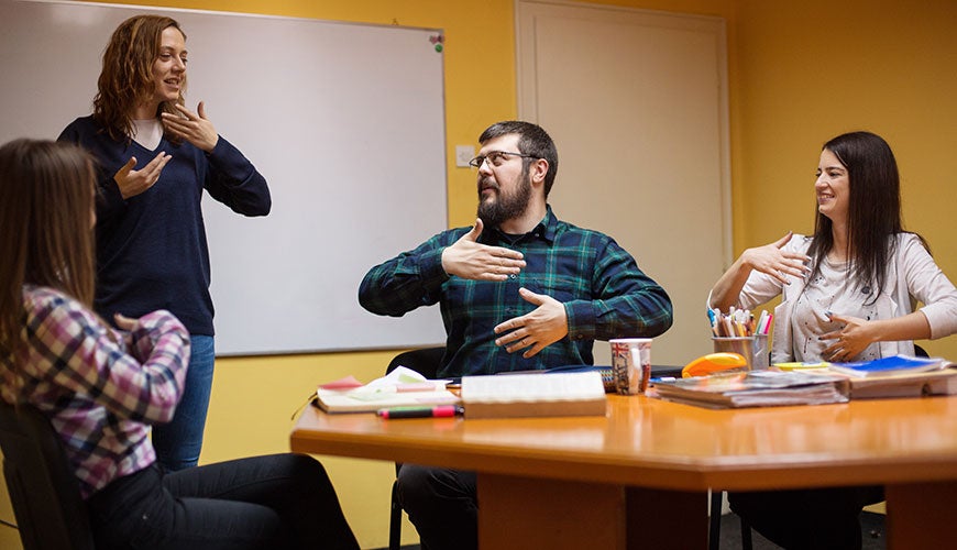 People in a staff meeting, communicating with sign-language
