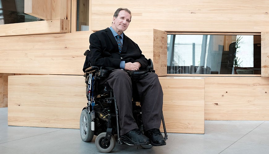 Simon Darcy sits in his wheelchair smiling