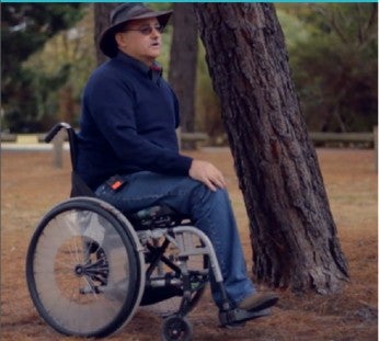 Mark Hopper sits in a wheelchair underneath a tree