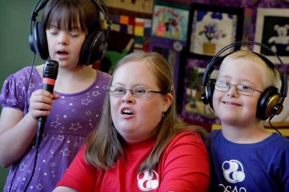 Three children with head phones and a microphone performing