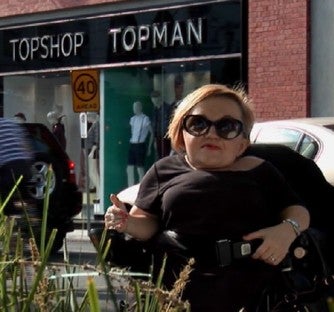 Stella Young in a wheelchair out the front of a Topshop