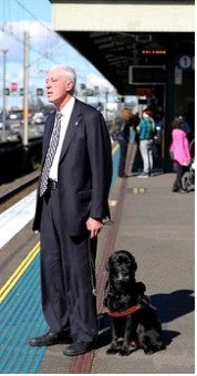 Graeme Inness at Train platform with guide dog