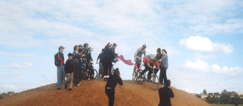 The official opening of the bike track, CHAMPS members riding through the ribbon while representatives of the media look on.