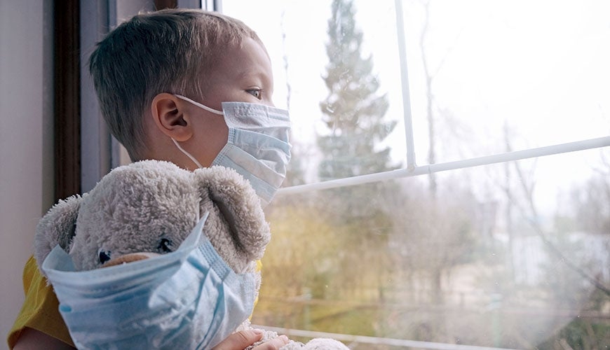 Sad child in quarantine with mask and masked teddy bear