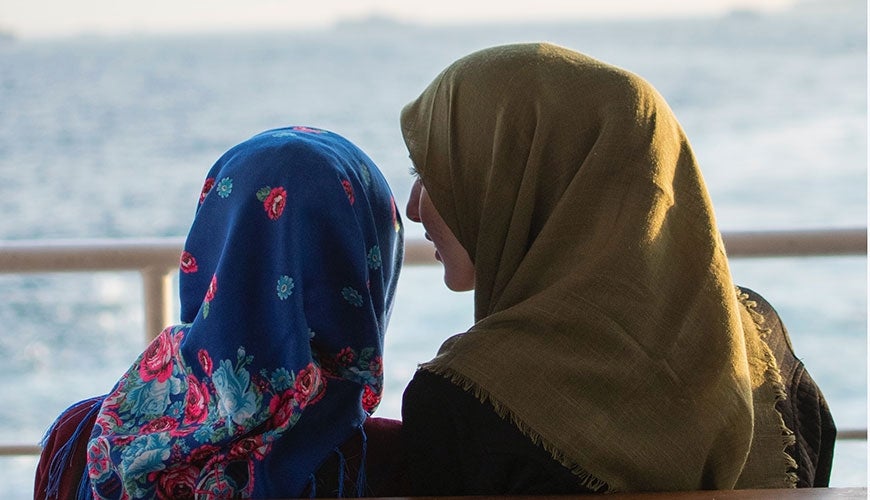 Two Muslim women talking near the ocean