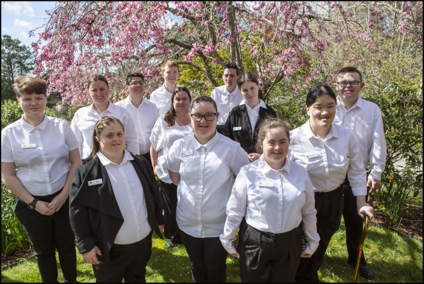 A group of 12 people - staff of Hotel Etico - standing in a garden