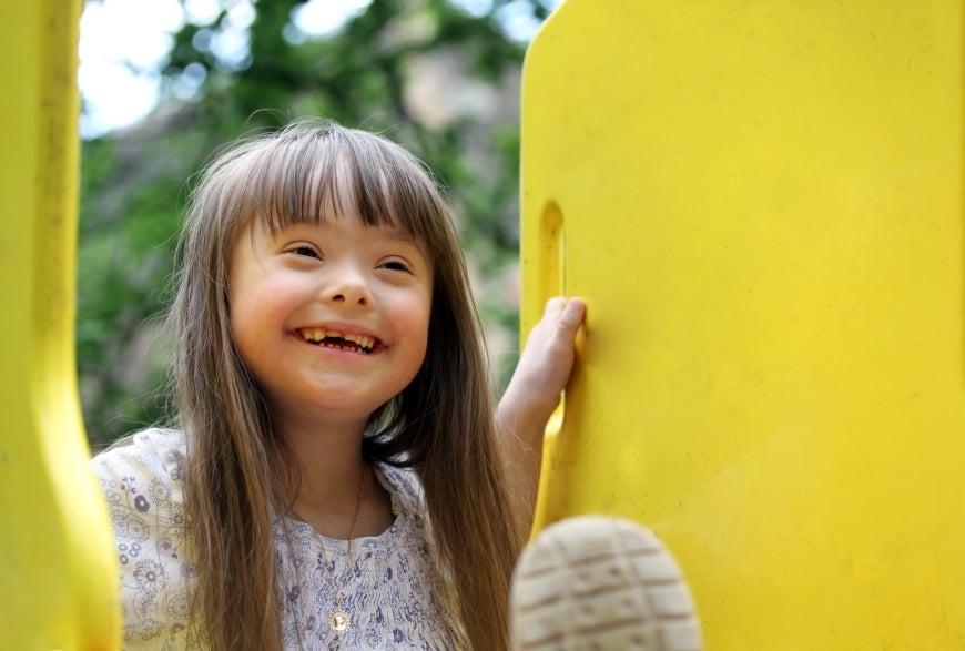 Smiling girl with down syndrome in a playground.