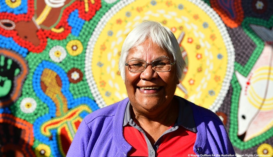 Jenny Ebsworth smiling in front of Aboriginal Art.