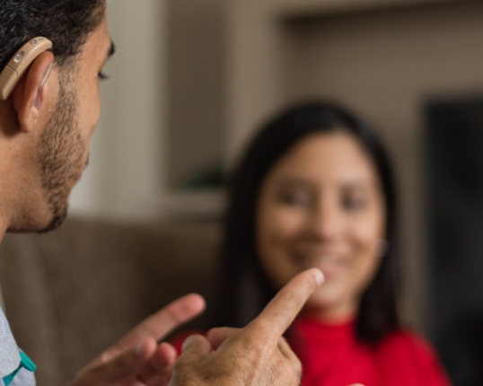 A person with a hearing aid speaking to another person.