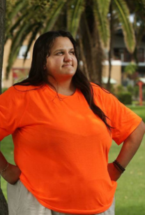 Picture of woman with long dark hair wearing orange shirt