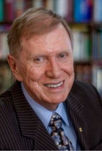 Smiling older man in black suit, blue shirt and tie