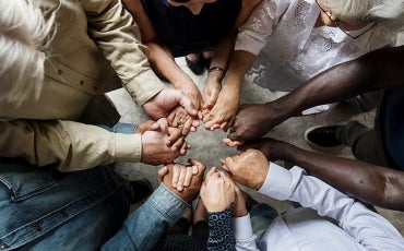 Group of diverse hands holding each other in supportive teamwork
