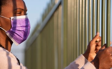 woman in facemask in detention fence