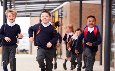 A group of children running at a school, wearing school uniforms