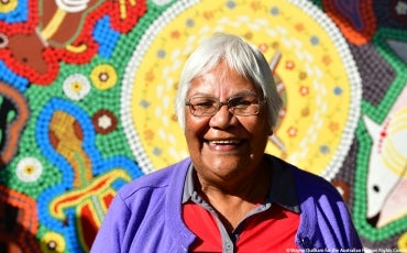 Jenny Ebsworth smiling in front of Aboriginal Art.