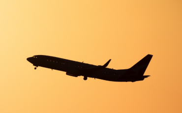 Anonymous airplane flies in the skies with setting sun in background