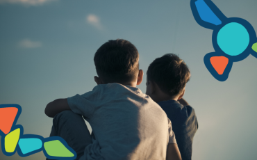 two boys sitting on the groud looking up to the sky