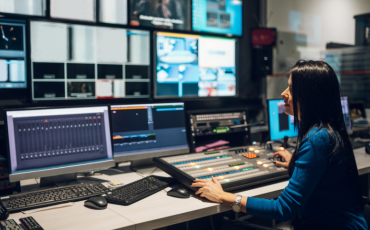 Person sitting behind the control panel inside a media control room