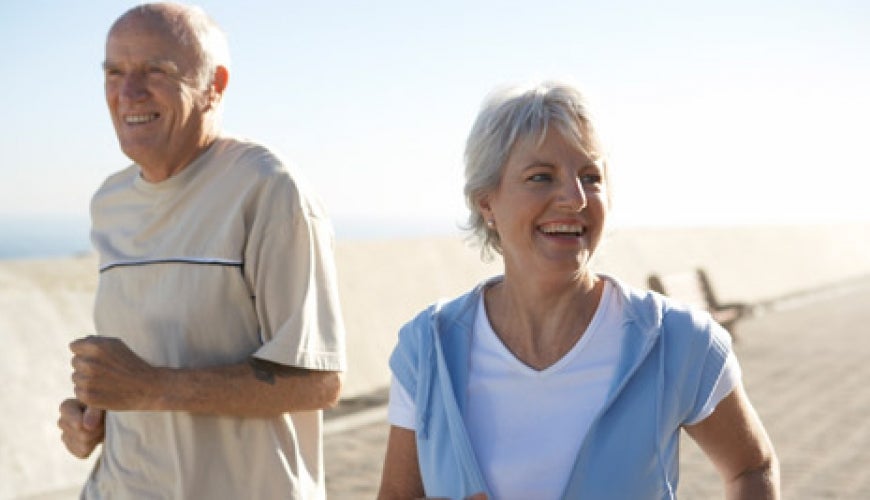 Photo: Older man and woman running on a beach