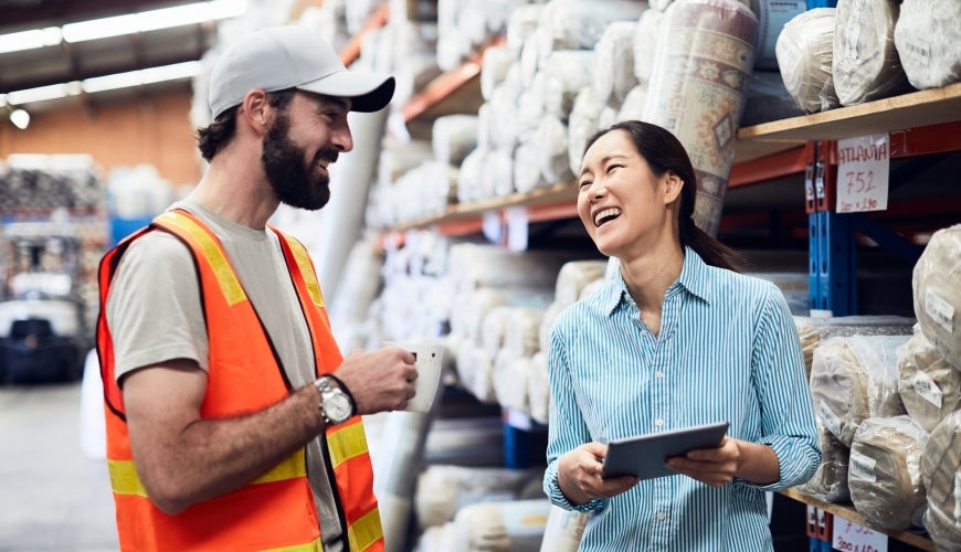 Asian woman and white man laughing while working in warehouse