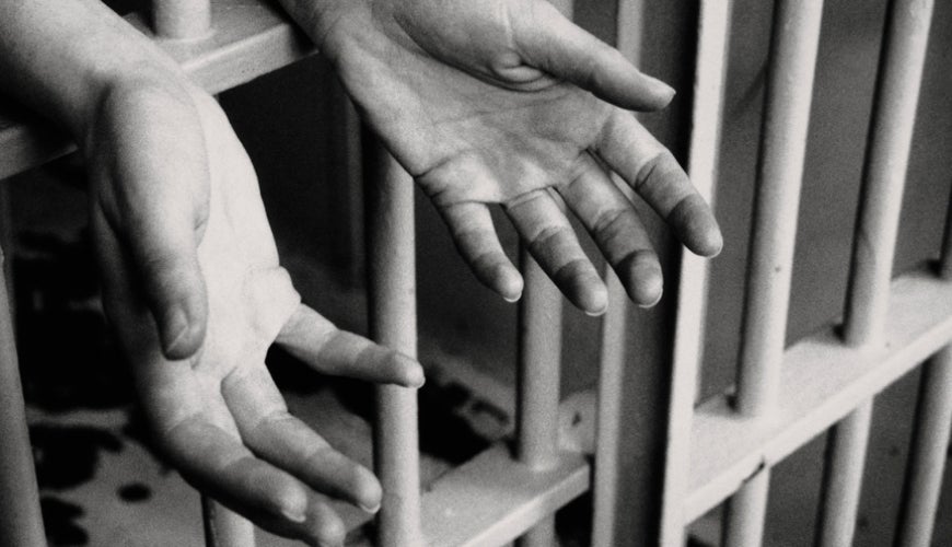 Hands reaching out through prison bars