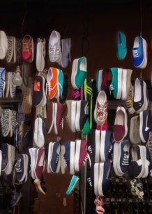 Image of a range of different colours and styles of sneakers hanging in a store front 