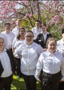A group of 12 people - staff of Hotel Etico - standing in a garden