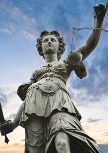 Outdoor metal statue of Justice with sky in background.