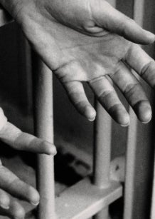 Hands reaching out through prison bars