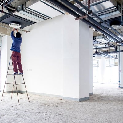 Worker on ladder fitting ceiling appliance