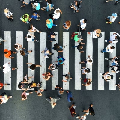 A busy street crossing with dozens of people walking back and forth, as seen from above.