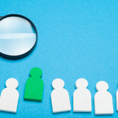 magnifying glass hovering over stand out candidate in a line of figures