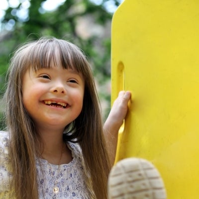 Smiling girl with down syndrome in a playground.