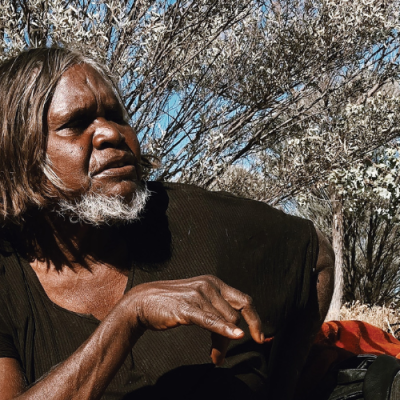 First Nations woman wearing black t-shirt sitting in the bush