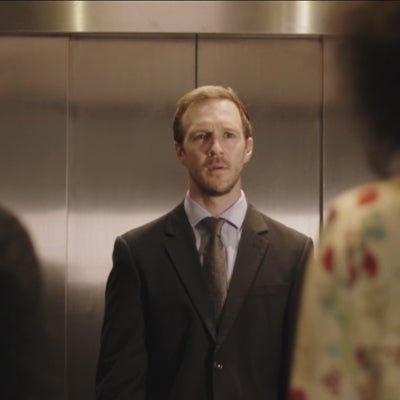 man starting at two women outside an elevator