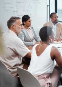 A group of employees sit around a table in a meeting room
